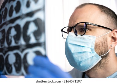 A Doctor In Glasses And A Medical Mask Examining CT Scan Of Patient's Lungs At Hospital. Diagnosis Of The Disease. Close-up.