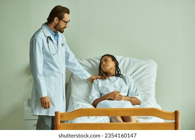 doctor in glasses standing near african american woman in hospital gown, private ward, patient - Powered by Shutterstock