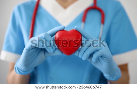 Doctor in gloves holds a red heart. Diseases of the cardiovascular system concept