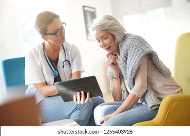  Doctor going through results and medication on tablet with senior patient                              