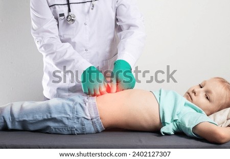 A doctor in green medical gloves is palpating the abdomen of a little seven-year-old girl. Stomach disease, gastritis and peptic ulcer in children, indigestion. Copy space for text