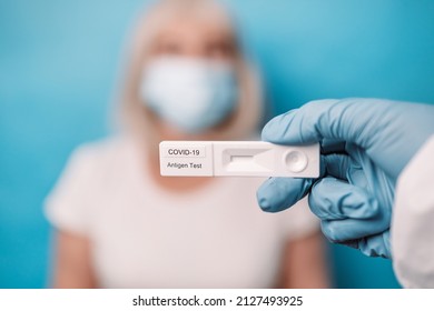 Doctor Hand In Blue Gloves Holding Rapid Lateral Flow COVID 19 Tests Over Bright Blue Color Background In Lab.