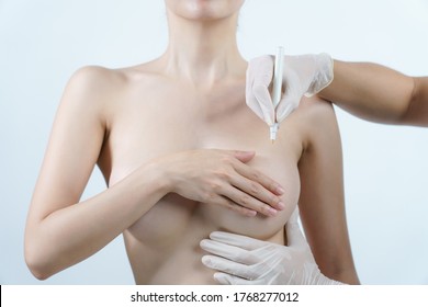 Doctor hand drawing lines on woman breast, breast implant surgery concept.