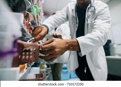 Doctor Hand Finding A Medicine In Hospital Pharmacy. Medical Staff Looking For Medicinal Drugs In Drugstore.