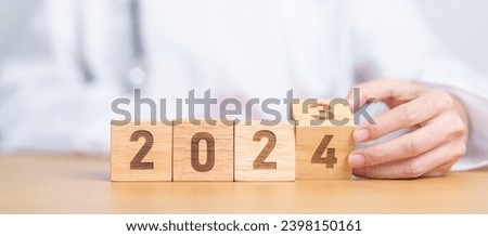 Doctor hand flipping 2023 to 2024 block. Happy New Year for Medical, Health care, Insurance and Wellness concepts