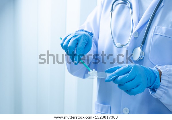 Doctor hand holding liquid base cytology set on
blue background.Gynecologist working for vaginal and cervix pap
smear patient in the obstetrics and gynecology department.Medical
concept.