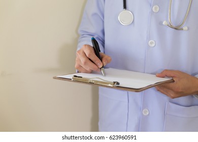 doctor hand holding pen writing something on clipboard. Medical care, insurance, prescription, paper work or career concept. Physician ready to examine patient and help - Shutterstock ID 623960591