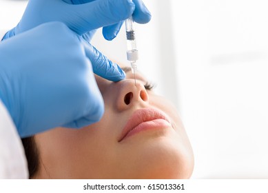 Doctor hand injecting in face of calm woman