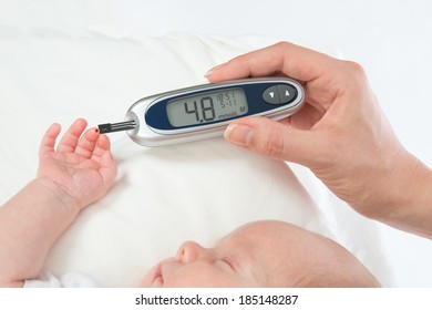 Doctor Hand Measuring Glucose Level Blood Test From Diabetes Patient Child Baby Using Glucometer And Small Drop Of Blood From Finger And Test Strips Isolated On A White Background