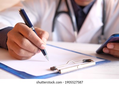 Doctor Hand Writing Prescription On Desk, Close Up.