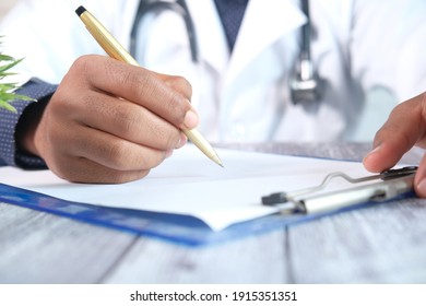 Doctor Hand Writing Prescription On Desk, Close Up.