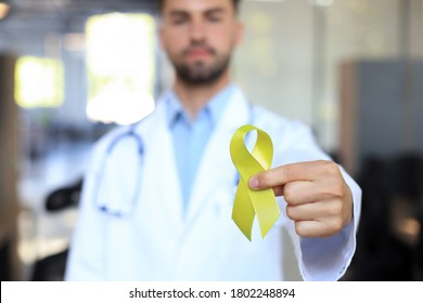 Doctor hand with yellow gold ribbon, sarcoma awareness, childhood cancer awareness, world suicide prevention day.