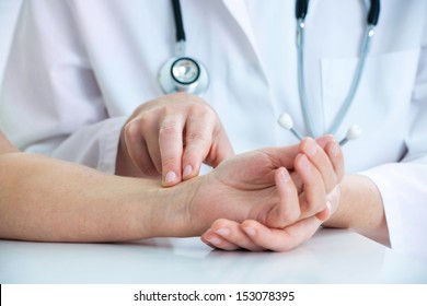 Doctor Hands Feeling Pulse On Male Wrist