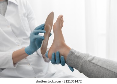 Doctor hands hold an orthopedic insole. Orthopedist tests the medical device. Orthopedic insoles on a white background. Foot care, comfort for the feet. Prevention of flat feet and foot diseases. - Shutterstock ID 2121361472