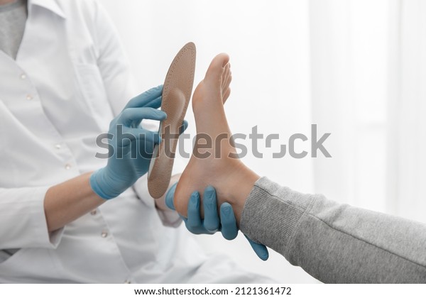 Doctor hands hold an orthopedic insole.\
Orthopedist tests the medical device. Orthopedic insoles on a white\
background. Foot care, comfort for the feet. Prevention of flat\
feet and foot diseases.