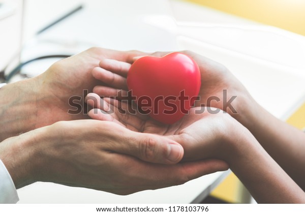 Doctor hands holding and giving red massage heart\
to patient little children for recover from sickness. Hospital and\
Healthcare concept. CPR and cardiology from heart attack and\
disease. Heart donate