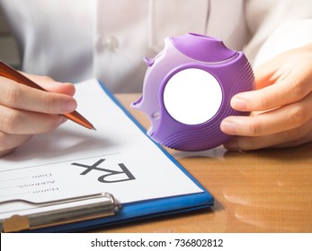 Doctor Hands Holding Medicine Dry Powder Inhaler And Writing Medical Prescription On Rx Form For Treatment Asthma/COPD Diseases On Physician's Desk At Hospital. Health Care And Medication Concept.