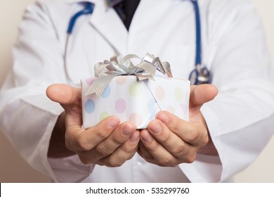 Doctor Hands Holding Small Gift With Ribbon.