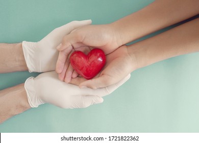 Doctor hands with medical gloves holding child hands and red heart, health insurance,organ donation, charity during covid coronavirus , saving life, thank you and appreciation to doctor