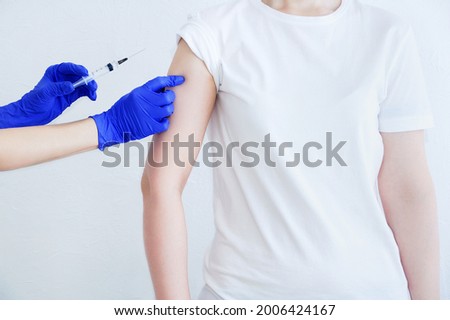 Doctor hands in medical gloves and a syringe. Vaccinating a Caucasian woman patient.