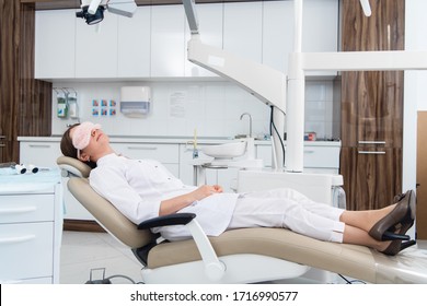 A Doctor Having A Nap In The Dental Chair Using A Sleeping Mask