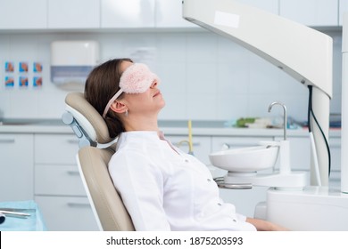 A Doctor Having A Nap In The Dental Chair Using A Sleeping Mask.