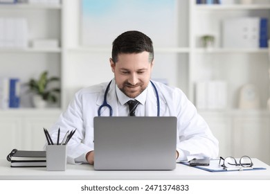 Doctor having online consultation via laptop at table in clinic - Powered by Shutterstock