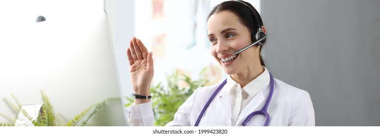 Doctor With Headphones And Microphone Waving Hand At Computer Screen