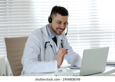 Doctor With Headset Consulting Patient Online At Desk In Clinic. Health Service Hotline