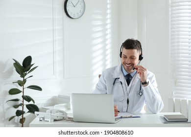 Doctor With Headset Consulting Patient Online At Desk In Clinic. Health Service Hotline