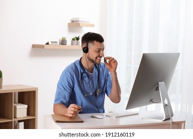 Doctor With Headset Consulting Patient Online At Desk In Clinic. Health Service Hotline