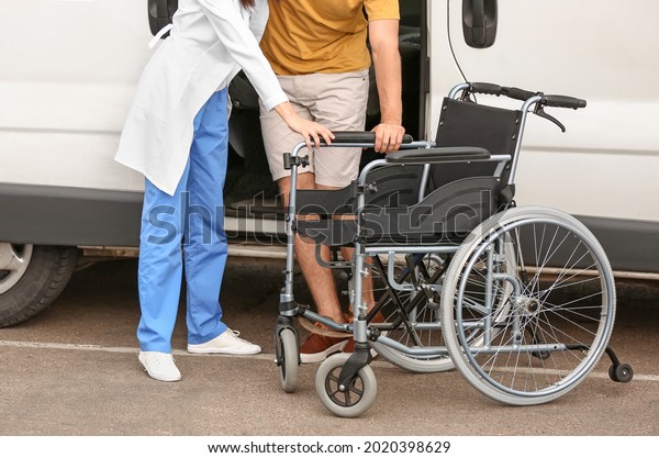 Doctor helping\
handicapped man to sit in\
car