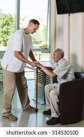 The Doctor Helping An Old Man Get Up From The Chair