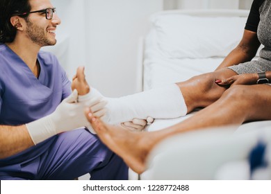 Doctor helping a patient with a fractured leg - Powered by Shutterstock