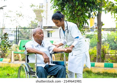 Doctor helping senior old patient to stretch hands during morning exercise while on wheelchair at hospital park - concept of physio, caretaker and therapy or treatment. - Powered by Shutterstock