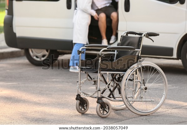 Doctor\
helping young handicapped man to get out of\
van