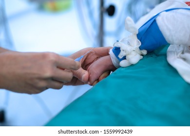 Doctor Hold Baby’s Foot For Injecting And Drawing Blood Sample In Cardiac Operating Room