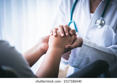 The Doctor Hold Hands Patient Which Sat On Wheelchair To Encourage To Fight The Disease And Cheer To Receive Treatment, To Health Care Concept.