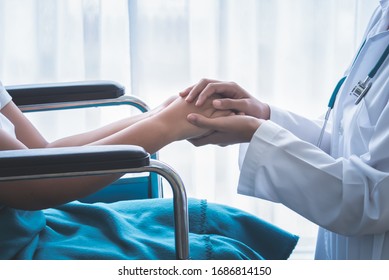 The Doctor Hold Hands Patient Which Sat On Wheelchair To Encourage To Fight The Disease And Cheer To Receive Treatment, To Health Care Concept.