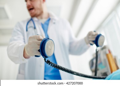 Doctor holding defibrallator in hands going to send a shock