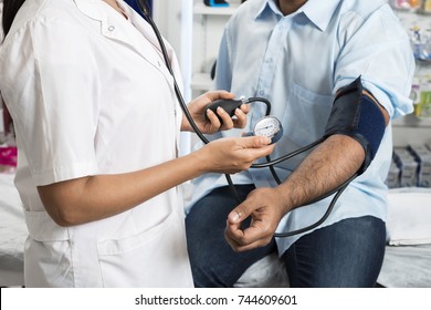 Doctor Holding Dial While Measuring Man's Blood Pressure