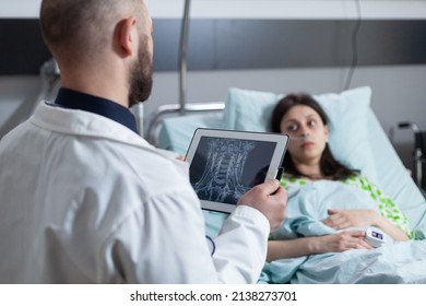 Doctor Holding Digital Tablet With Mri Scan Of Throat Area Reading Diagnosis To Concerned Patient On Hospital Bed Recieving Oxygen. Medic Explaining Cervical Injury To Woman With Low Spo2 Saturation.