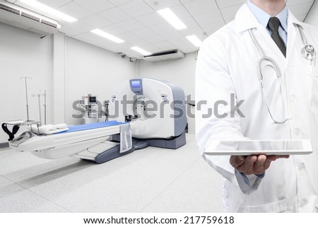 doctor holding a digital tablet for presenting at computed tomography or computed axial tomography scan machine in hospital room 