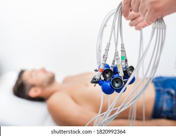 Doctor holding ECG electrodes for heart diagnostic over mature man. Medical equipment for electrocardiogram close up