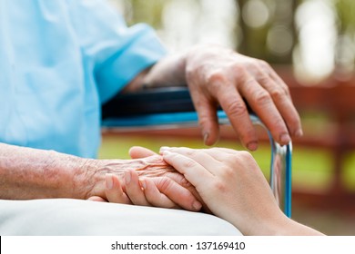 Doctor holding elderly patient 's hand in a wheelchair. - Powered by Shutterstock