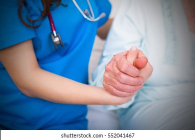 Doctor holding elderly patient's hands, supporting her in hardships.