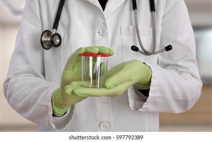 Doctor holding empty container for urine or sperm samples in hands