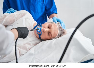 Doctor holding endoscope during gastroscopy in hand while patient is laying at the bed