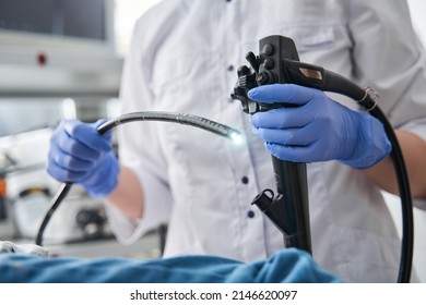 Doctor holding endoscope during gastroscopy in hand while little girl patient laying