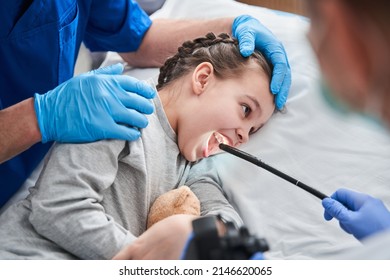 Doctor holding endoscope while making gastroscopy for the little girl